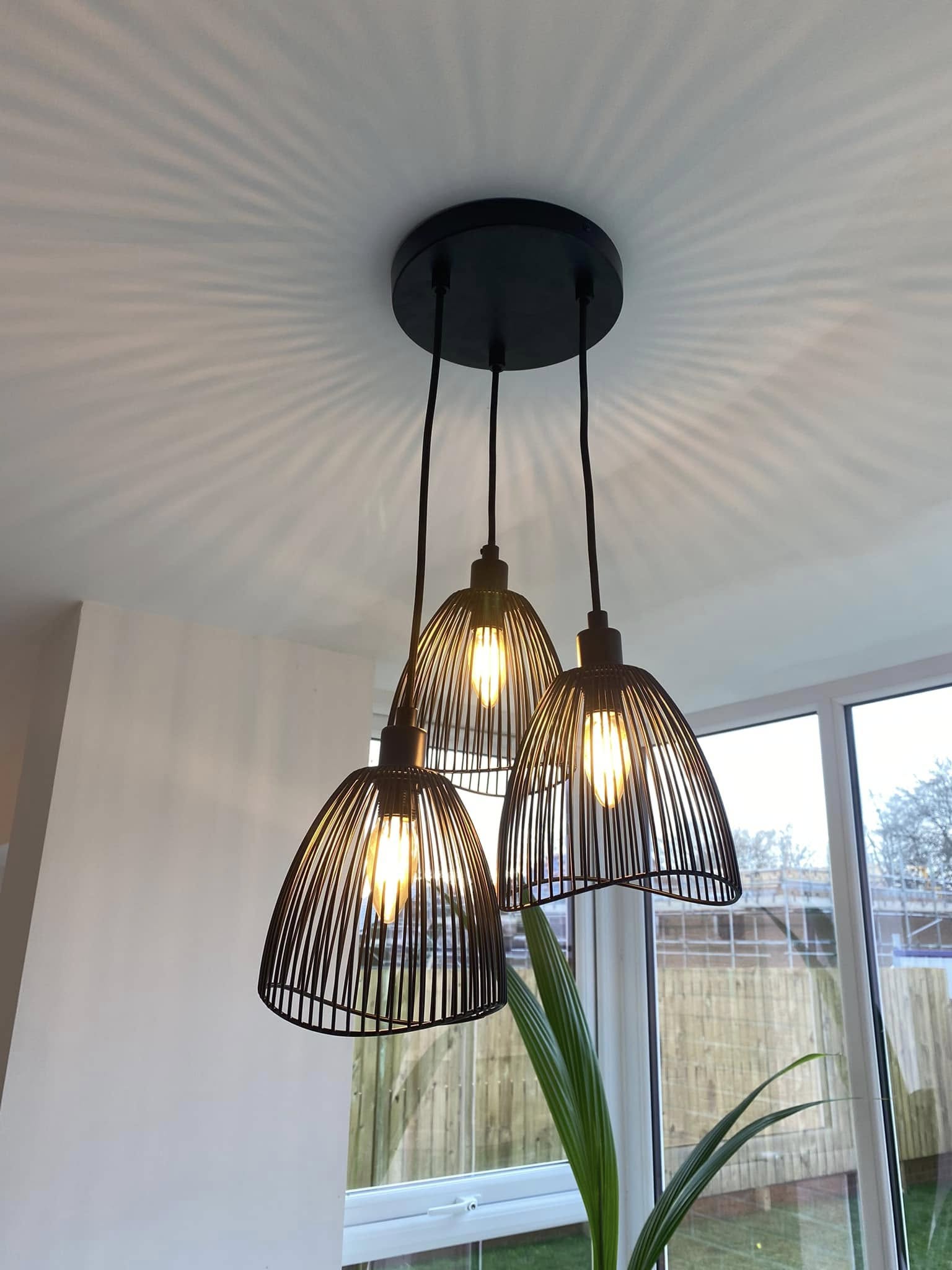 A cluster of cage pendant lights fitted by JCES, throwing a fan of light across the ceiling
